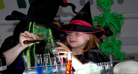 A woman and girl dressed as witches make potions.