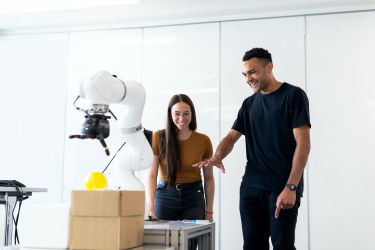 The image selected as the TechEthos website homepage banner shows two innovators discuss a robotic arm. 