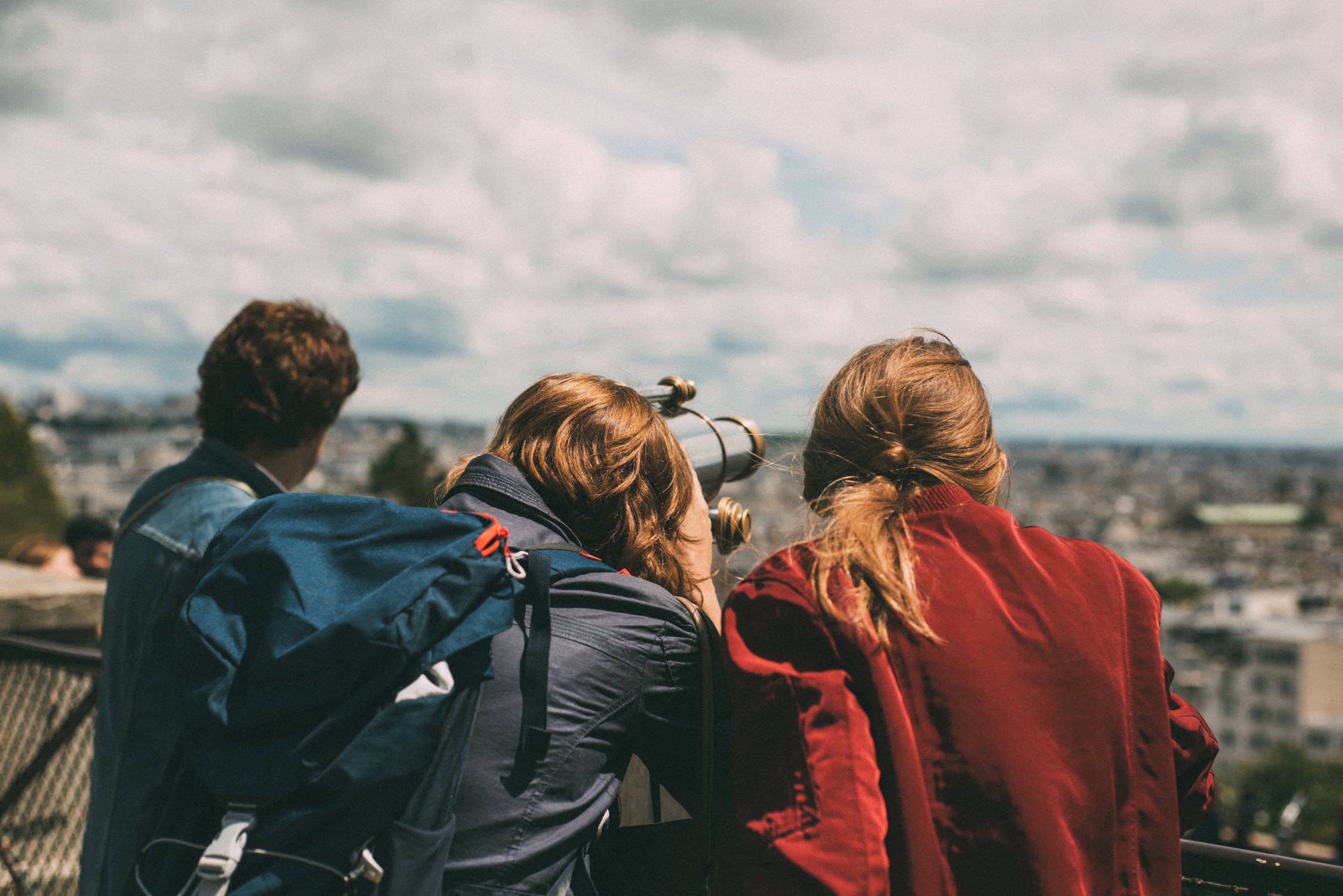 three young people using a telescope