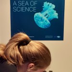 A young adult looking through a microscope in one of the compartments of the Escapebox Ocean Eye