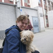 photo of Anna kneeling down and smiling with a dog on a street in Beijing, China
