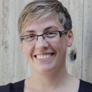 Marianna Obrist headshot, short hair, glasses, big smile